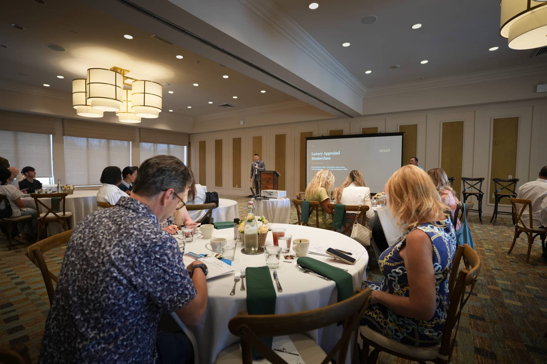 Christopher Molina at the podium presenting the Luxury Appraisal Masterclass to a room of seated real-estate agents